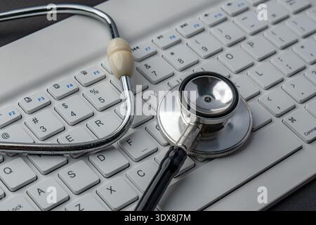 Stethoscope on a white keyboard. Computer troubleshooting, PC diagnostics, IT system health, and technical repair services concept. Stock Photo