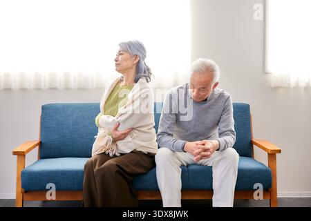 Senior couple sitting on a sofa in the living room after a fight Stock Photo