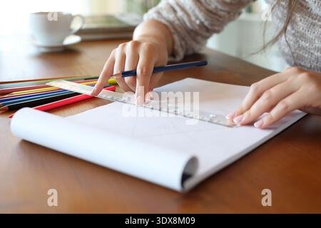 Close up of a woman hands using measuring rule on notebook in a wooden table at home Stock Photo