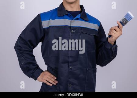 Worker in blue uniform holding a wrench Stock Photo