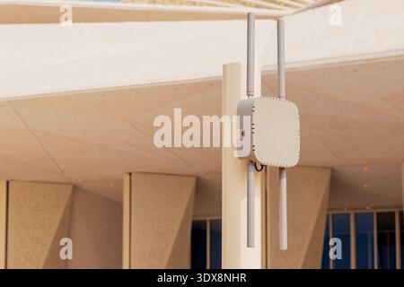 Outdoor wireless access point mounted on a pole, providing high speed Wi Fi connectivity to a modern building Stock Photo