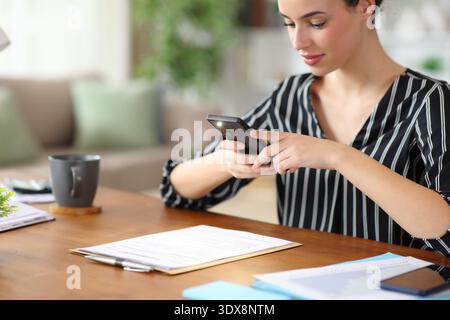 Freelance worker taking photo of form with smart phone working at home Stock Photo