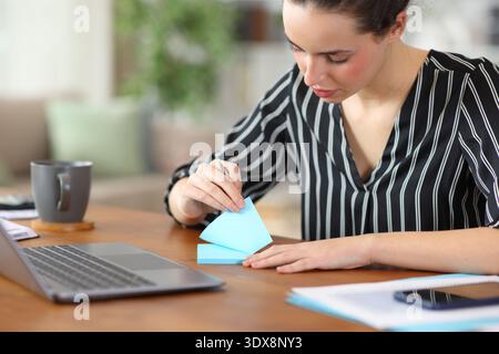 Serious tele worker using blue sticky note working at home Stock Photo