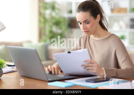 Shocked self employed checking documents working online at home Stock Photo