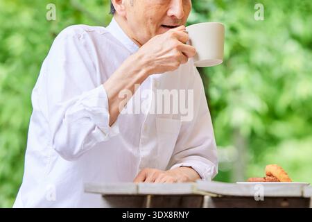 Senior man drinking coffee on terrace Stock Photo