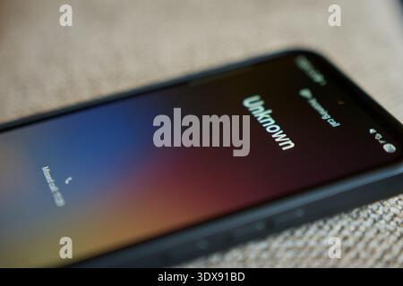 Close up of smartphone with unknown incoming call on screen. Concept of mobile communication, spam call risk and privacy concern. Stock Photo