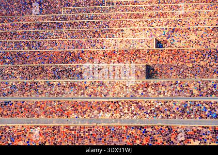 Architectural detail of stairs decorated with small colorful mosaic tiles forming an abstract pattern and textured surface Stock Photo