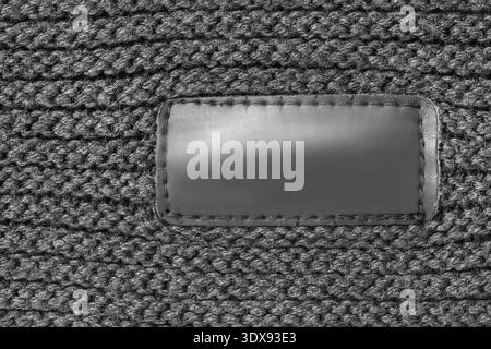 Blank black clothes patch label stitched on black yarn knit background Stock Photo