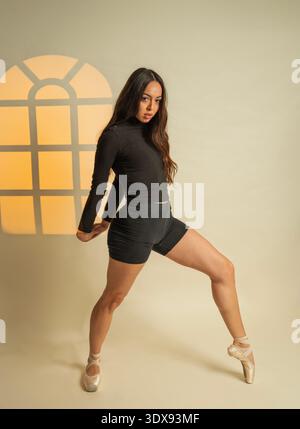 Ballerina performing dance movement en pointe in a brightly lit studio Stock Photo
