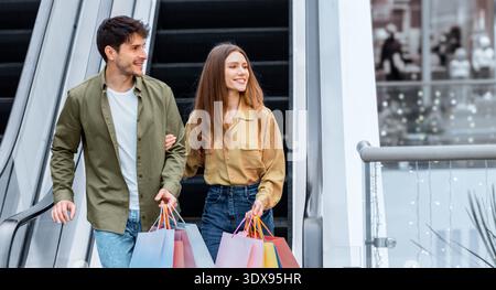 Couple Shopping Together While Using Escalator in a Shopping Mall During Daytime Stock Photo