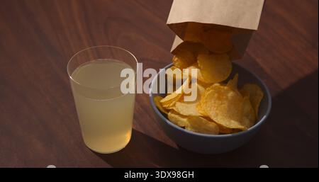 Man hand pour potato chips to blue bowl with ginger beer on background Stock Photo