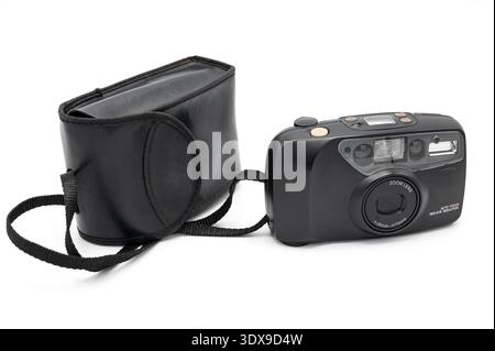 Vintage black 35mm compact analog film camera with original case and strap, featuring a 38-70mm zoom lens and built-in flash, isolated on a white back Stock Photo