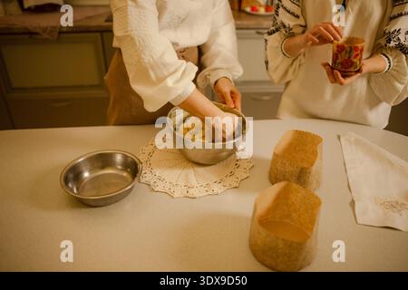 woman kneads dough for traditional Easter cake, sister helps and prepares baking pans Stock Photo