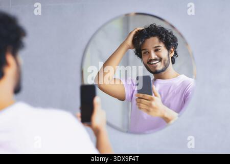 Man Taking Selfie While Looking in Mirror and Smiling During Morning Routine Stock Photo
