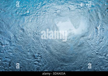 Abstract textured blue background showing rough metal material with droplets and bright light reflecting on its uneven surface Stock Photo