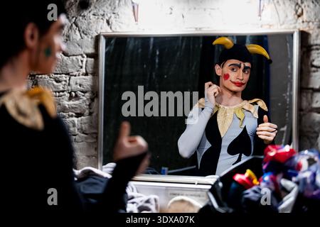 Man ballerino in jester costume reflecting in mirror in theater Stock Photo