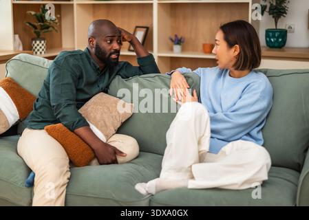 Two partners sitting on a couch, enjoying each other’s company in a stylish and inviting indoor setting. Stock Photo