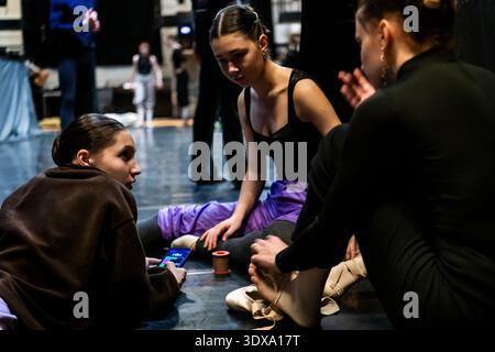Three ballerinas adjusting pointe shoes and taping feet backstage Stock Photo