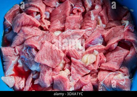 Freshly Cut Raw Meat Cubes in a Blue Container Stock Photo