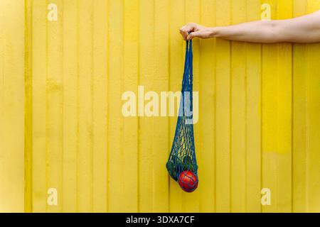 Eco-friendly mesh tote with fresh veggies isolated on yellow background Stock Photo