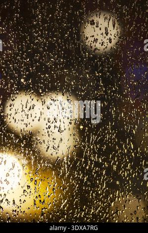 Drops on glass. Raindrops on a window against the backdrop of city lights at night. Raindrops on a window pane Stock Photo