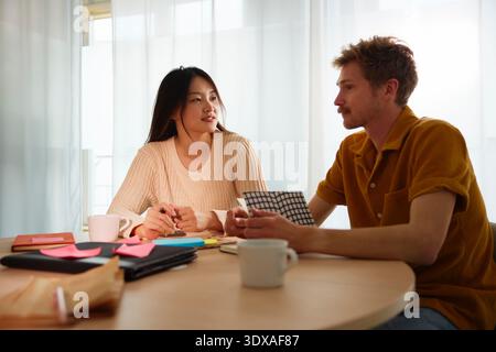 Female and male business professionals discussing ideas with each other while sitting at table in office Stock Photo