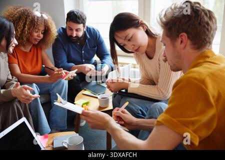 Female business entrepreneur reading document on clipboard held by male colleague in office Stock Photo
