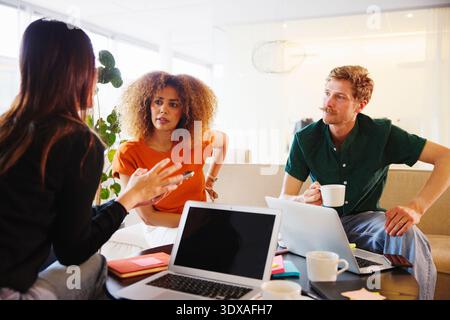 Multiracial male and female business employees listening to coworker while discussing strategies in office Stock Photo