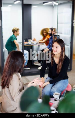 High angle view of female business manager talking with young female while sitting in coworking office Stock Photo