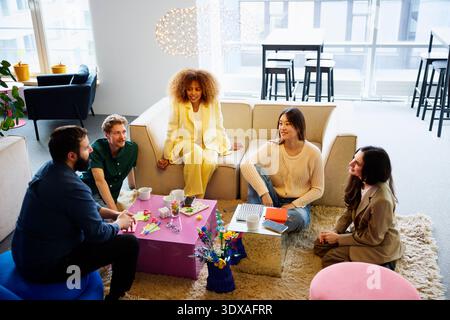 High angle view of multiracial group of business experts talking with each other while sitting in office lobby Stock Photo