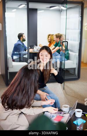 High angle view of smiling young businesswoman talking with female colleague in office lobby Stock Photo