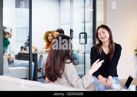 Happy young female business expert sitting with manager in office lobby Stock Photo