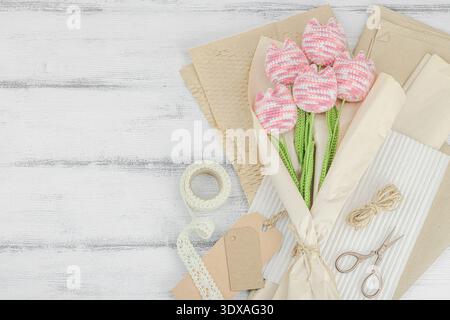 Handmade gift bouquet of crocheted pink tulips wrapped in craft paper. Sustainable celebration decor with eco friendly packaging for hypoallergenic we Stock Photo