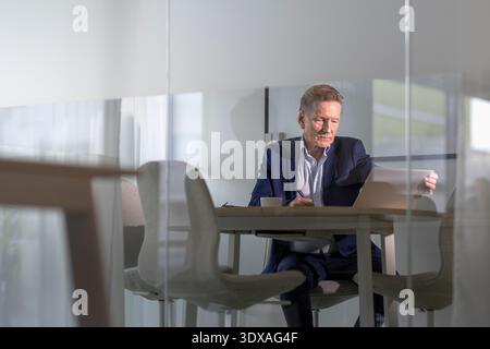 Senior male entrepreneur working on laptop while sitting at office Stock Photo