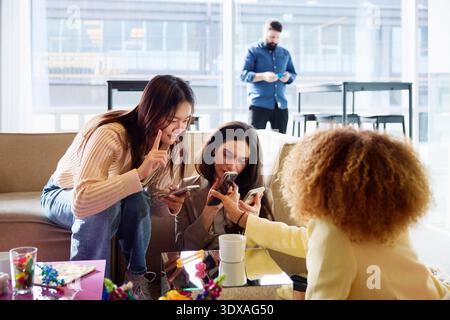 Female business experts using smart phone while spending leisure time in office lobby Stock Photo