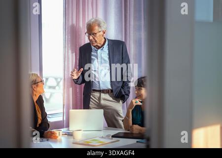 Senior manager sharing marketing ideas with colleagues in meeting room Stock Photo
