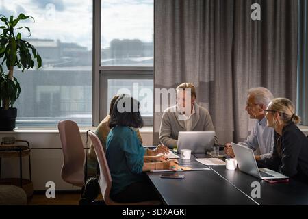 Team of senior corporate professionals sitting around table during office team meeting Stock Photo