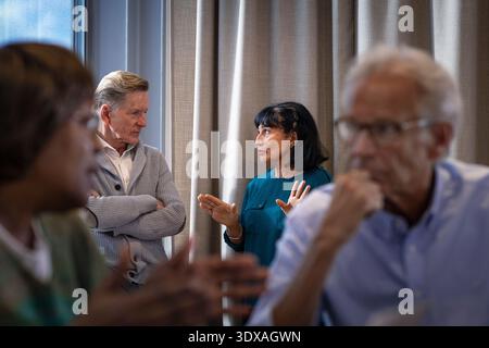 Female business expert discussing with male colleague while standing near curtain of window in office Stock Photo