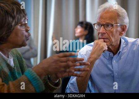 Senior businessman with hand on chin listening to female colleague during meeting in office Stock Photo