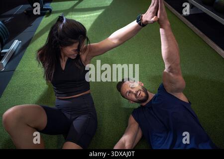 High angle view of male and female friends giving high-five while exercising in gym Stock Photo