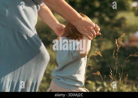 Mother holding hands of son walking in garden Stock Photo
