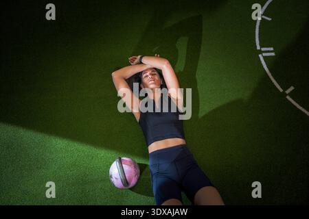 High angle view of tired female athlete lying on floor in gym Stock Photo