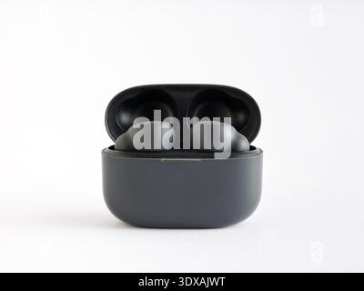 Black wireless earbuds resting in their open charging case, providing portable audio technology for modern living and music listening Stock Photo