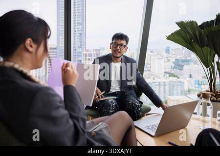 Young male entrepreneur sitting with colleague in office meeting Stock Photo