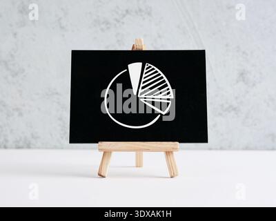 Pie chart icon on a small black chalkboard, displaying data analysis, market share, and financial growth concepts Stock Photo