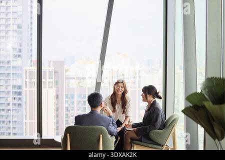 Smiling businesswoman sitting coworkers in team meeting at office Stock Photo