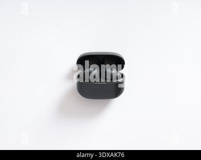 Black wireless earbuds resting within their charging case, ready for use. Modern audio technology for music and calls Stock Photo