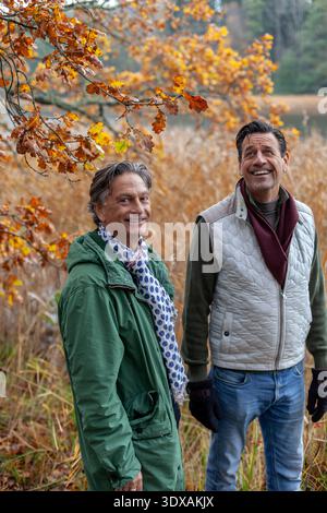 Happy senior male friends spending leisure time in forest during autumn season Stock Photo