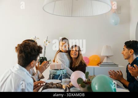 Family clapping for girl while celebrating birthday at home Stock Photo