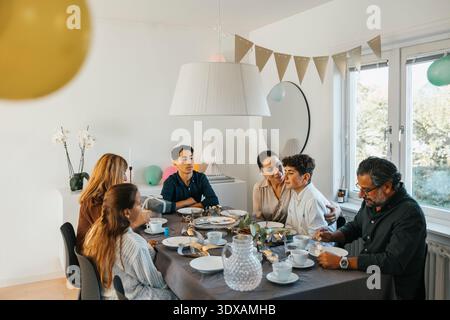 Happy family eating lunch while sitting around dining table Stock Photo